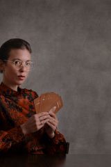 Photo of author Maude White. The author wears glasses and holds cards from the Pleasure Alchemy deck. She has a mysterious look on her face.