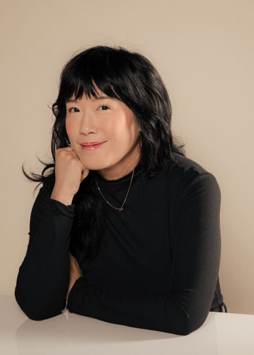 Photo of author Eileen Lee sitting a table smiling at the camera